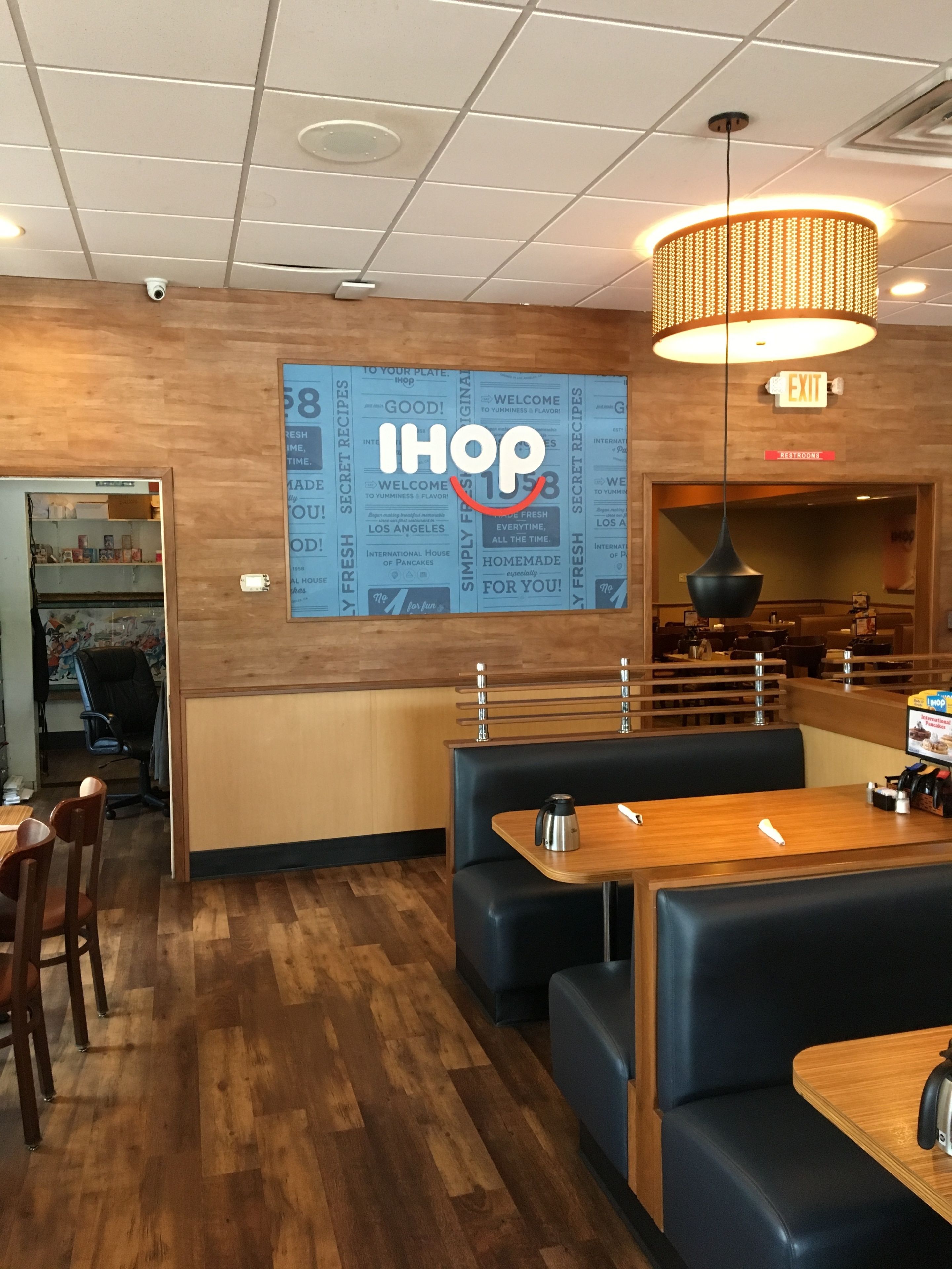 A restaurant interior with booths, tables, a large IHOP sign, and a visible exit sign.