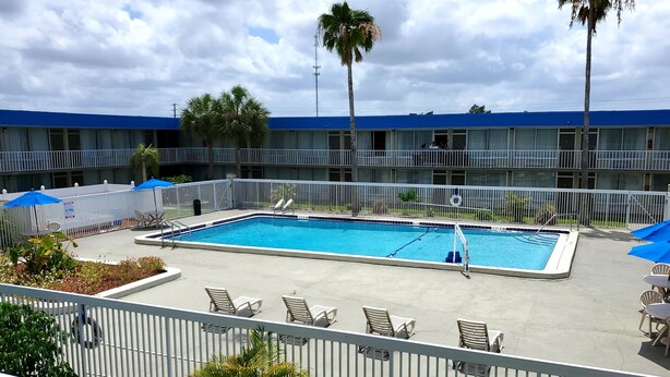 A hotel with a swimming pool, outdoor seating, and a blue-roofed building.