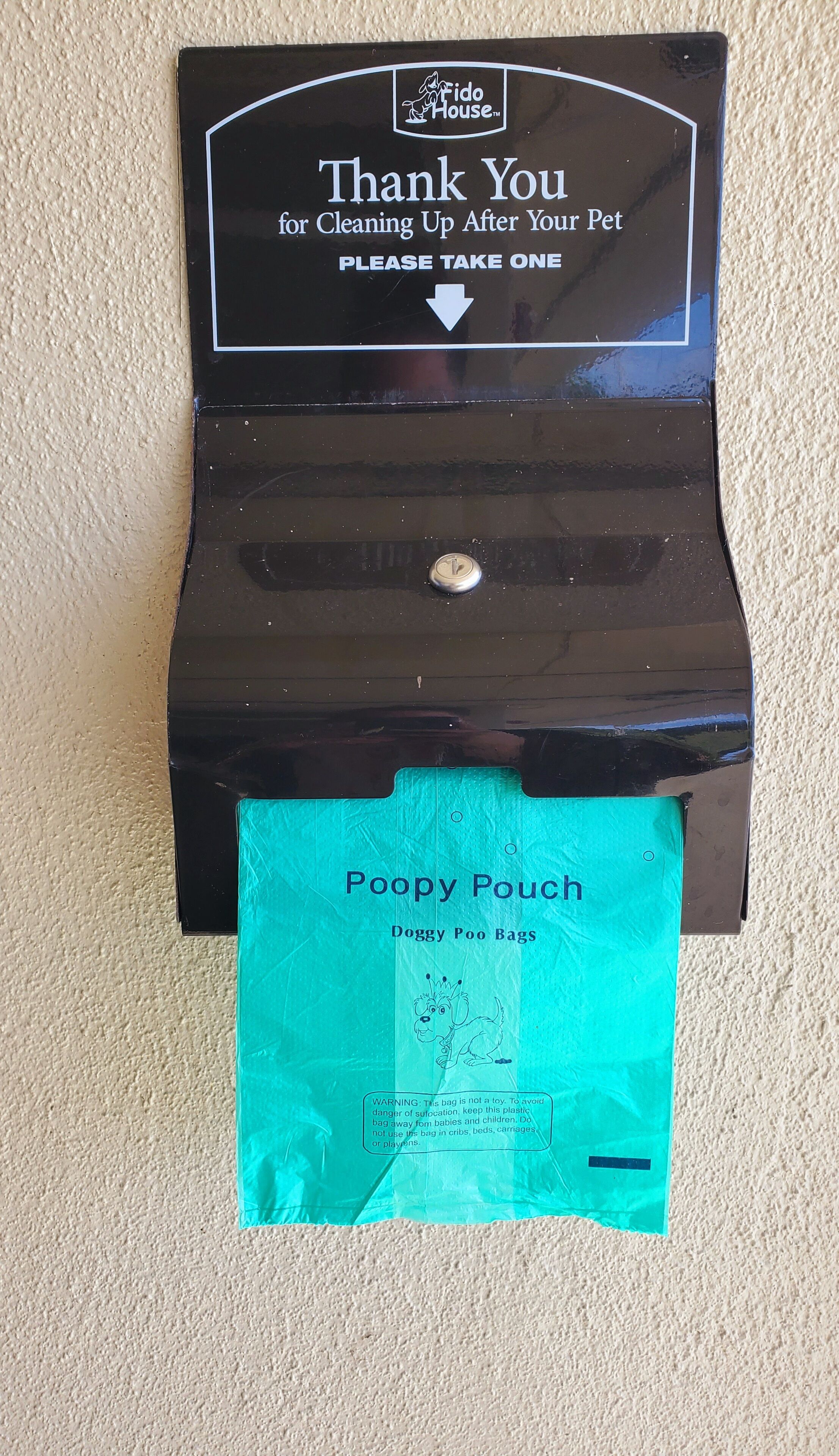 A black box with a sign that says "Thank You for Cleaning Up After Your Pet" and a blue bag labeled "Poopy Pouch" hanging from it.