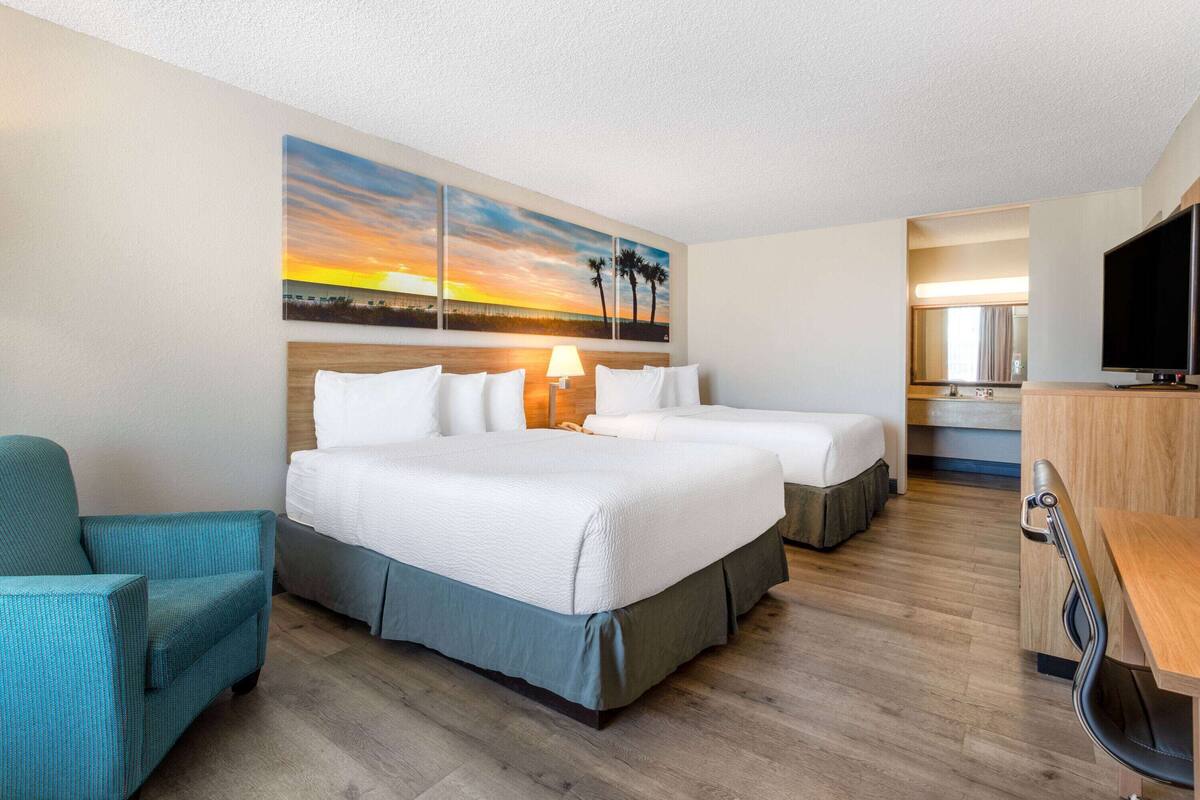 Ein Hotelzimmer mit einem großen Bett, einem Schreibtisch, einem Stuhl und einem Fernseher.