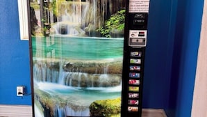 Ein Getränkeautomat mit Wasserfallanzeige, der sich in einem Raum mit blauen Wänden und Fliesenboden befindet.
