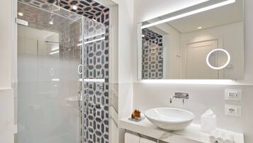 Une salle de bain moderne avec une douche à parois de verre, un lavabo blanc et un grand miroir.