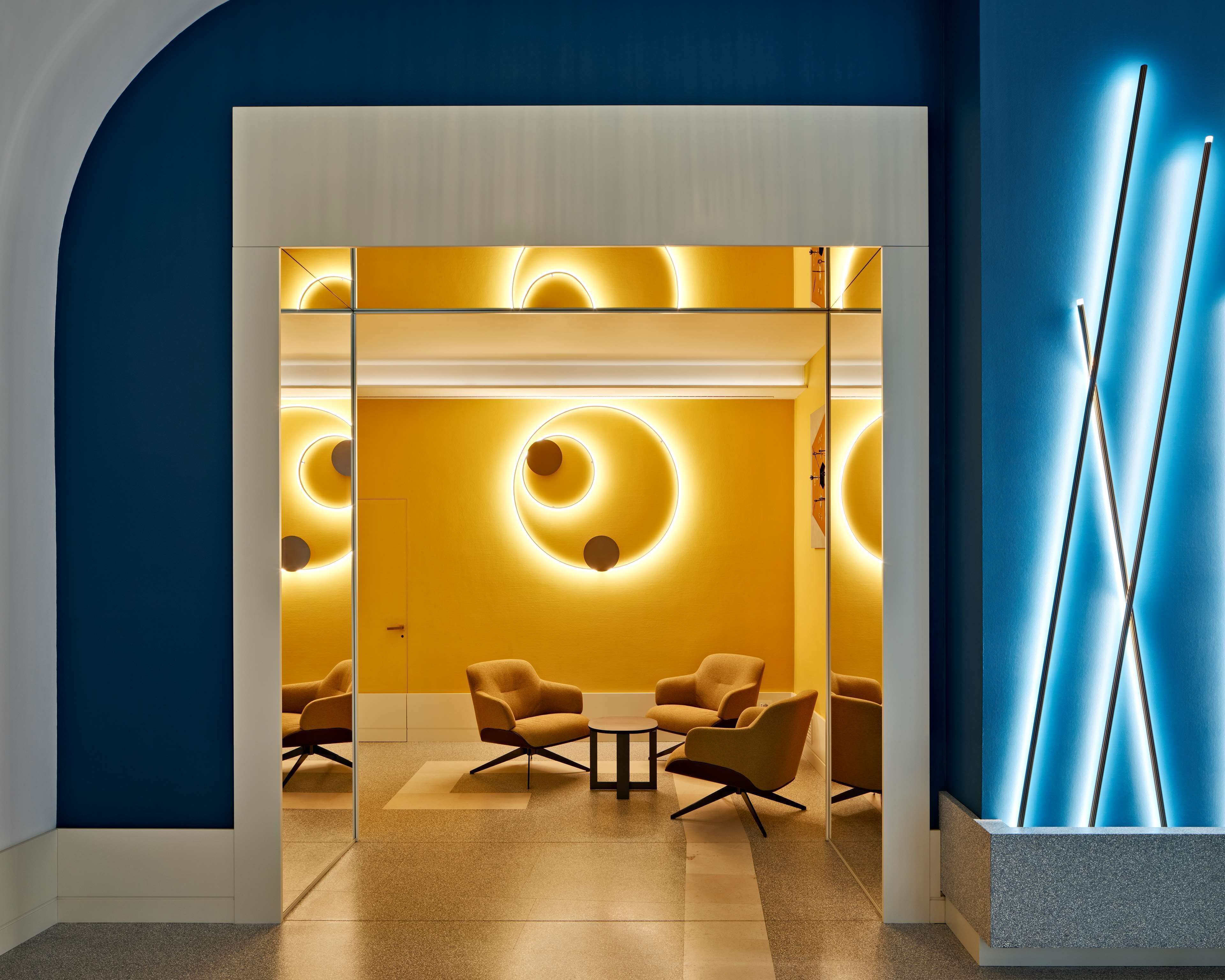 A modern interior with a glass partition, a round table, and two armchairs.
