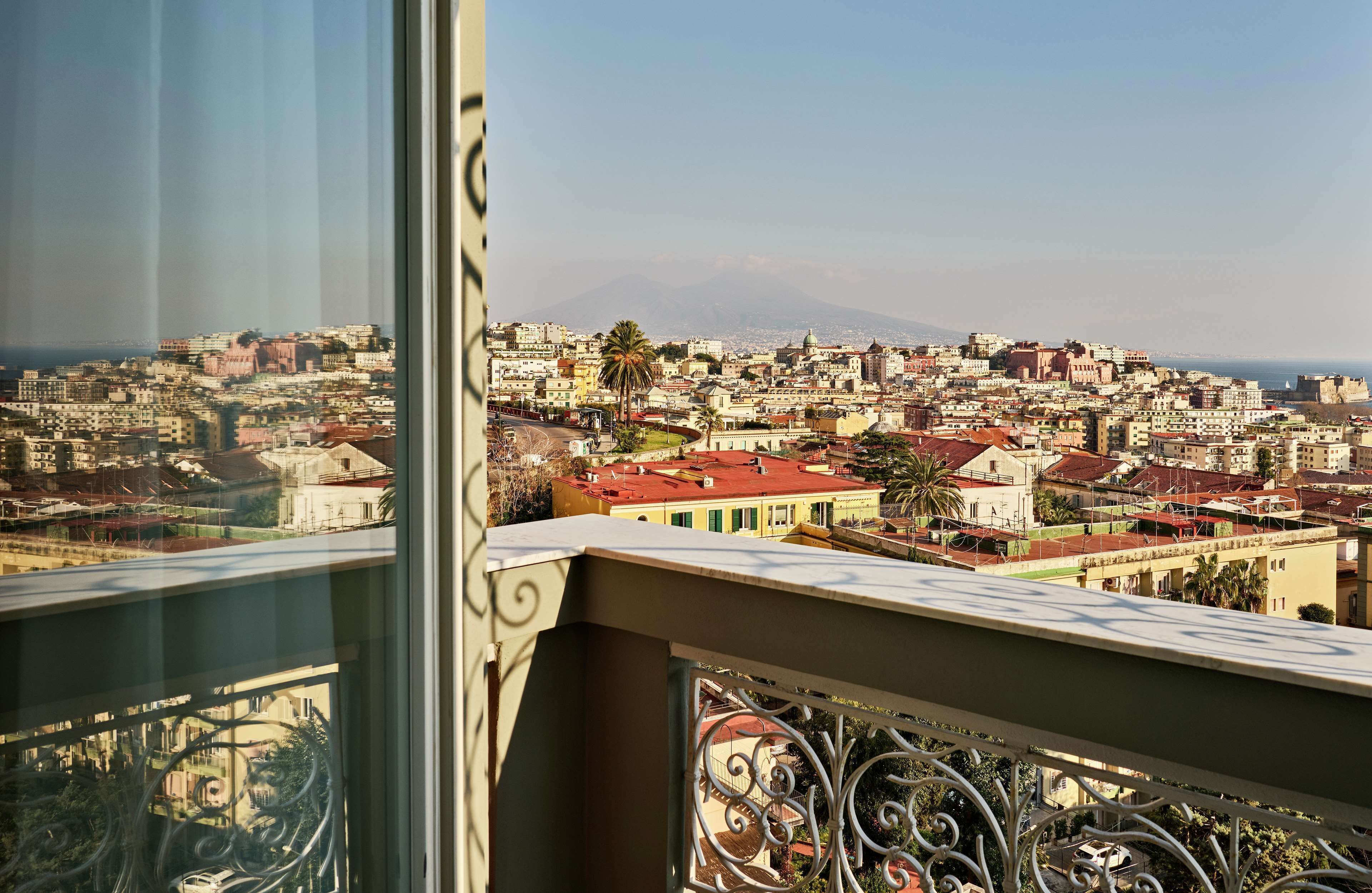 Un balcón con vistas a un paisaje urbano, que incluye edificios y una montaña distante.