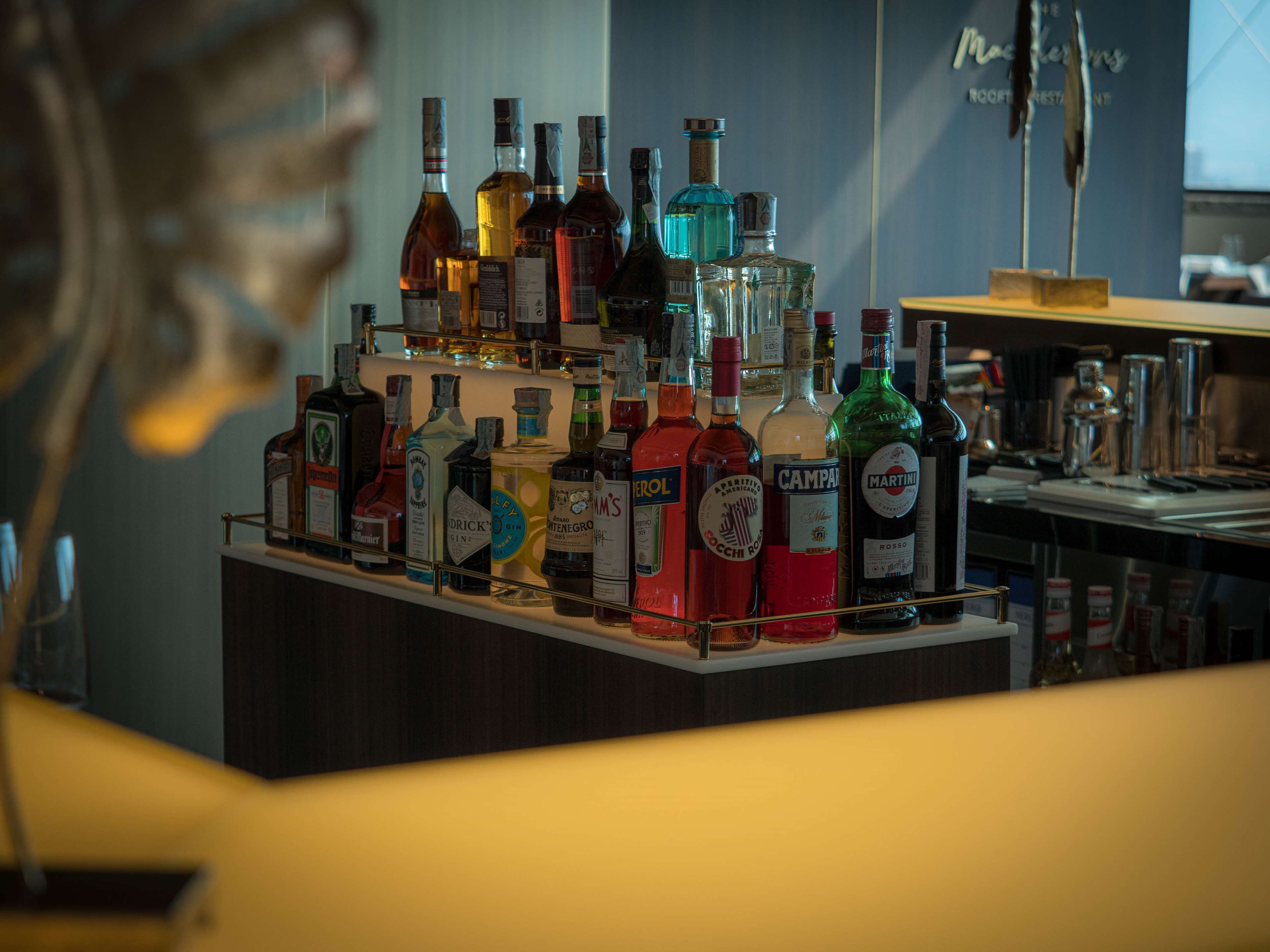 Angolo bar con diverse bottiglie di liquore e un bancone.