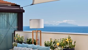 A balcony with wicker furniture, a large potted plant, and a lamp. - De Bonart Naples, Curio Collection by Hilton (Naples)