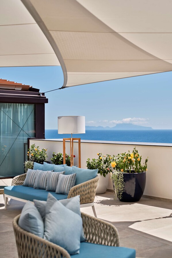 A balcony with wicker furniture, a large potted plant, and a lamp. - De Bonart Naples, Curio Collection by Hilton (Naples)