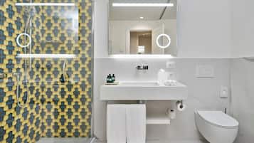 Un baño moderno con pared estampada, un lavabo blanco, un espejo con iluminación, un inodoro y una zona de ducha.