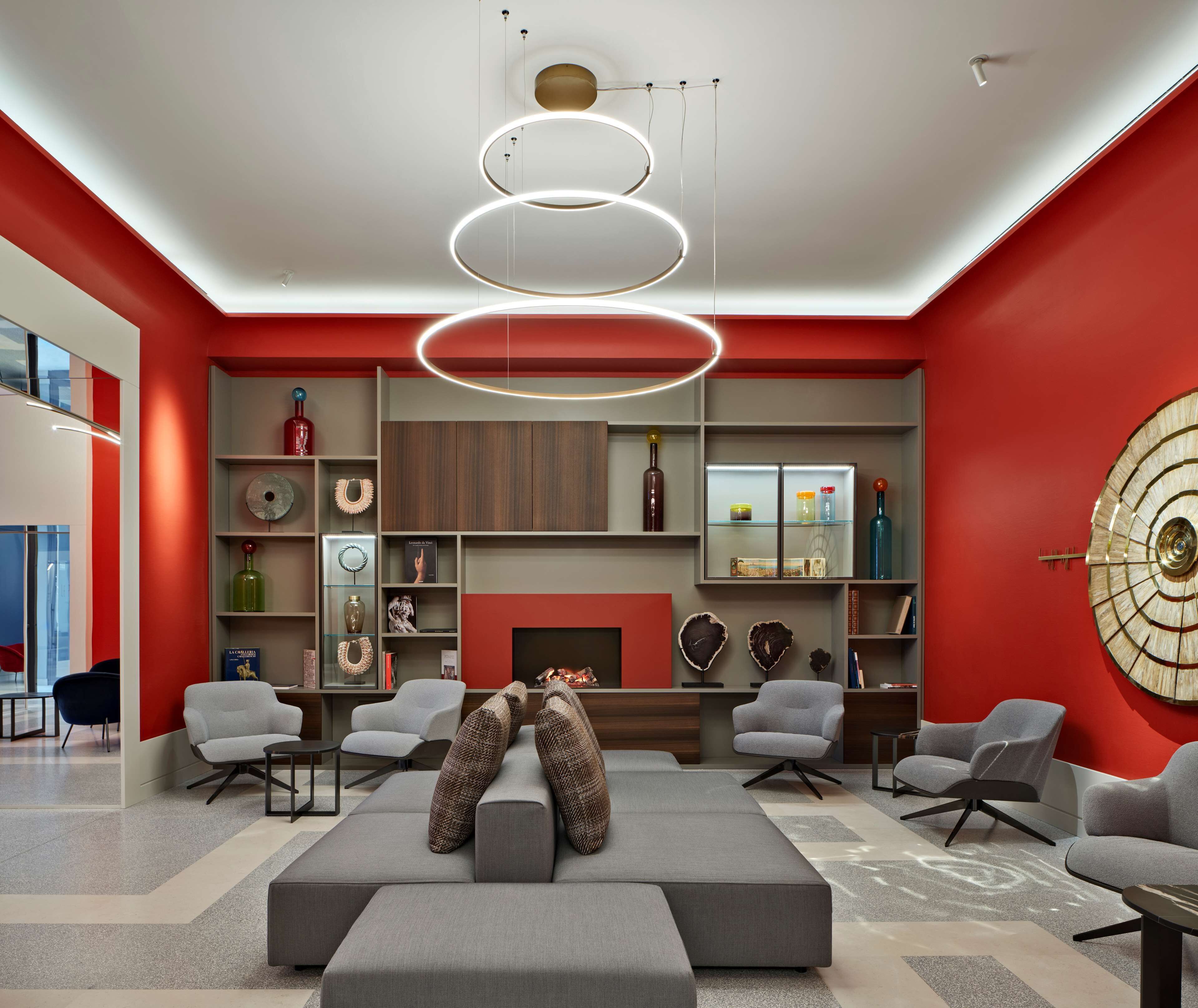 Un soggiorno moderno con camino, divani grigi e una parete decorata in rosso.