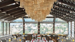 A breakfast buffet with various fruits and beverages, a modern chandelier, and a view of the city through large windows. - De Bonart Naples, Curio Collection by Hilton (Naples)