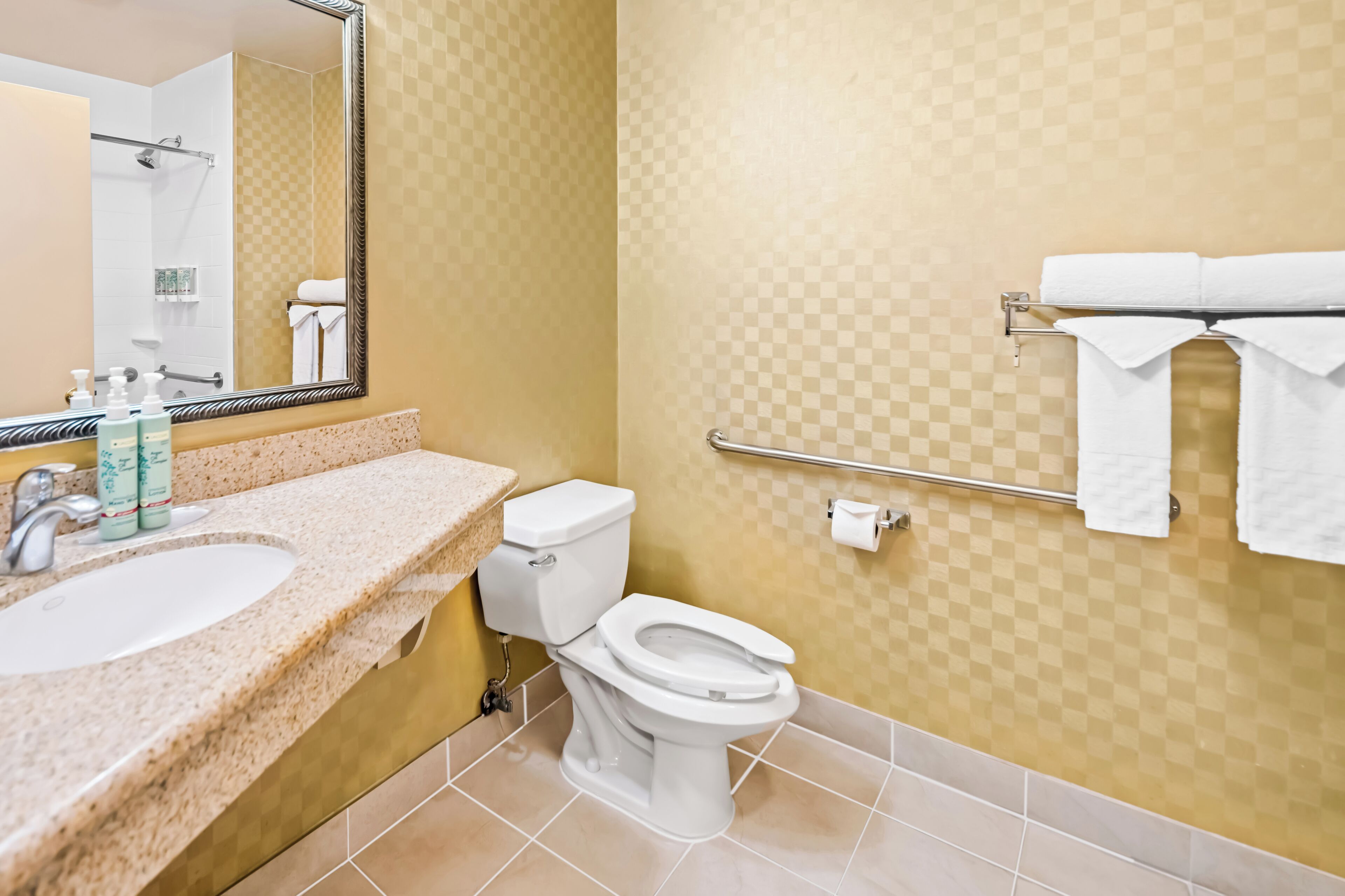Un baño con lavamanos, inodoro y toallero.