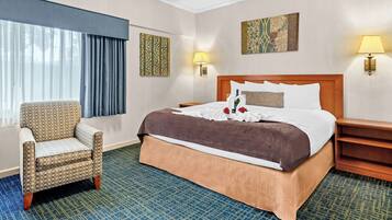 A hotel room with a large bed, a chair, a nightstand, and two wall-mounted lamps.