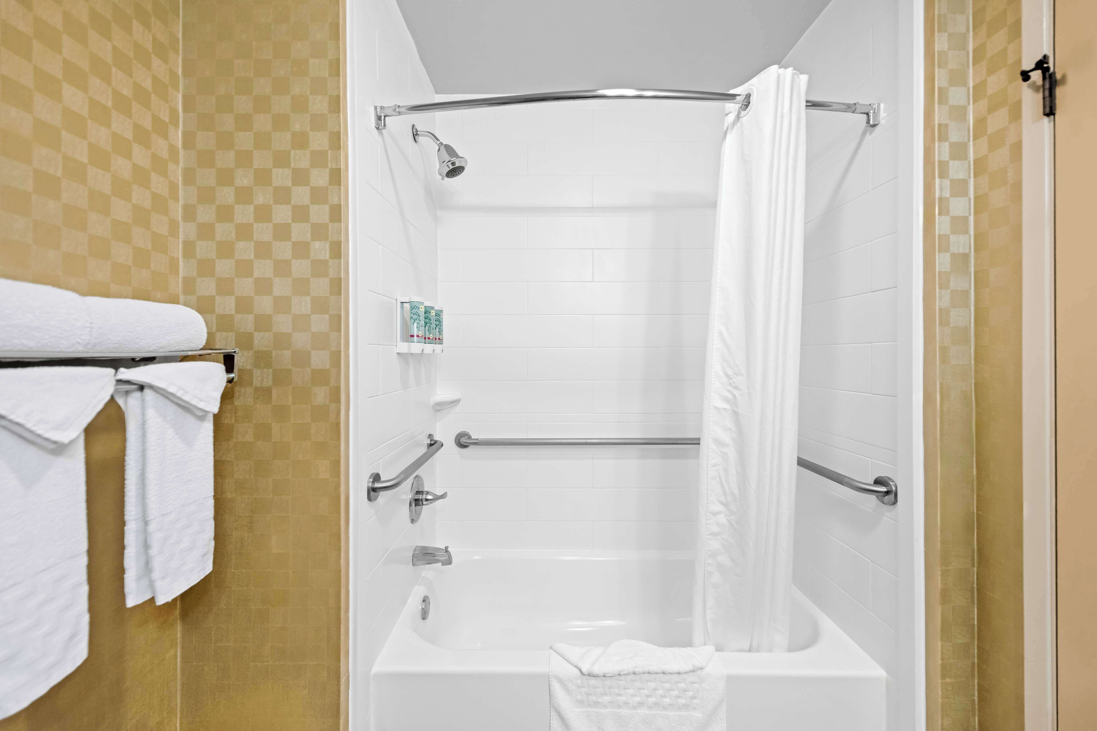 Un baño con bañera, cortina de ducha y un toallero con toallas.