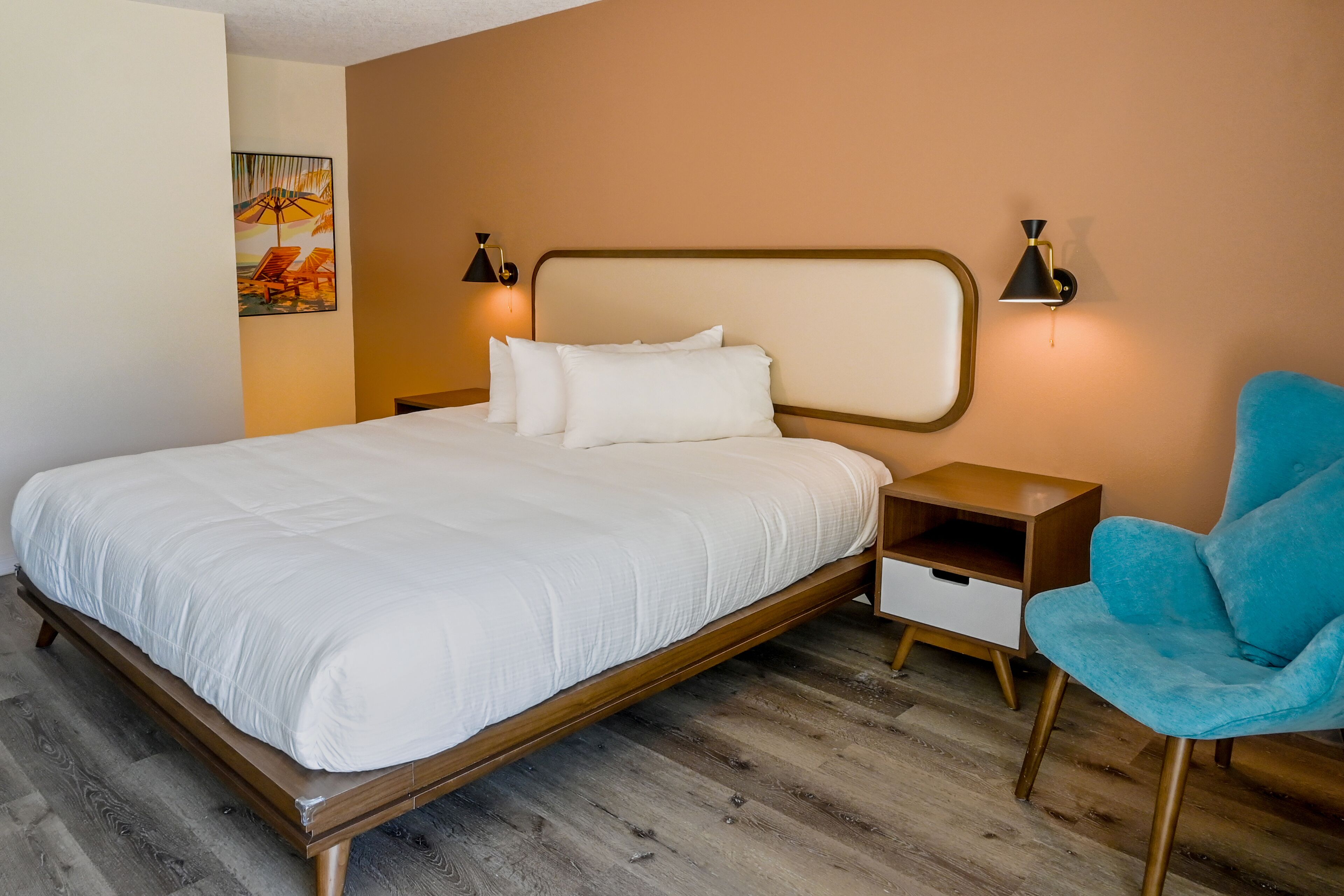 Un lit bien fait, avec une literie blanche, une tête de lit en bois et deux lampes de chevet.