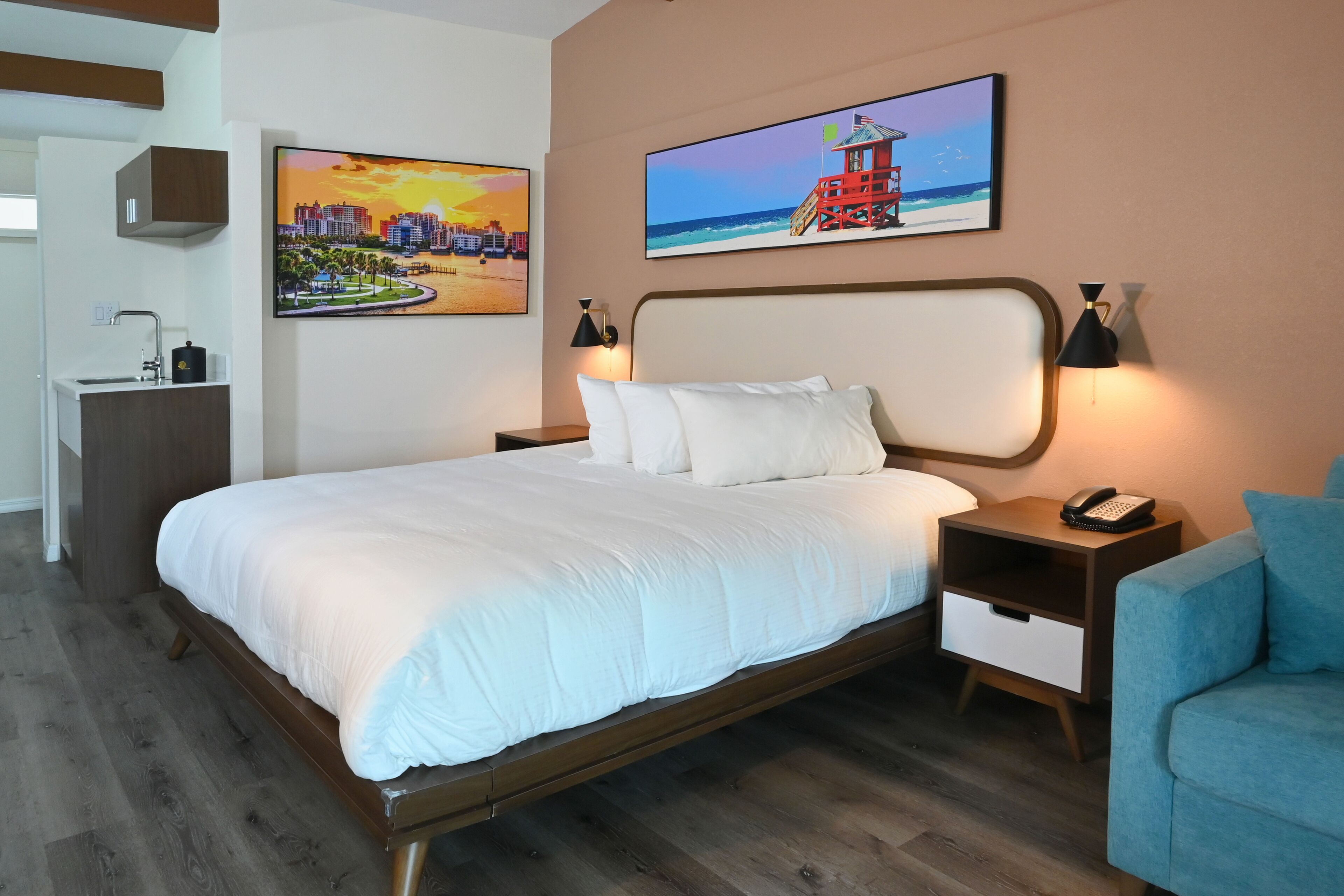 A modern hotel room with a large bed, a nightstand, a desk, and a chair.