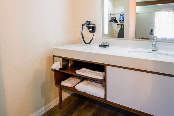 A bathroom with a white sink, a mirror, a hairdryer, and a towel rack.