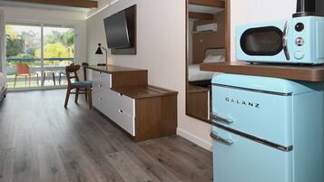 A compact kitchen with a Galanz microwave, wooden cabinets, a TV, and a balcony with outdoor seating.