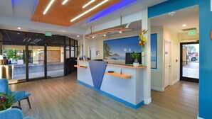 A reception desk with a beach mural, wooden flooring, and blue and orange decor.