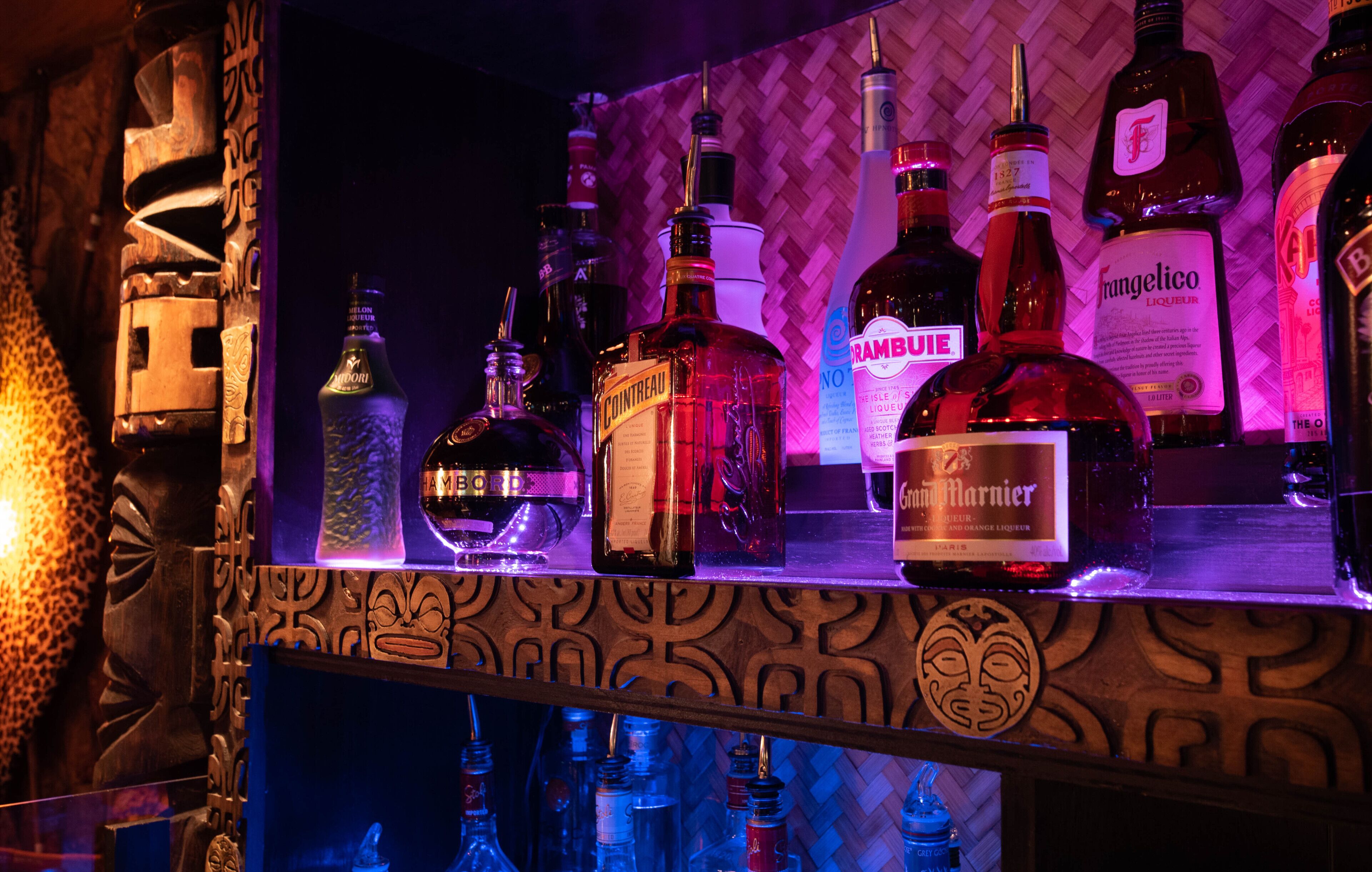 Un bar amb diverses ampolles de licors i un panell de fusta decoratiu.