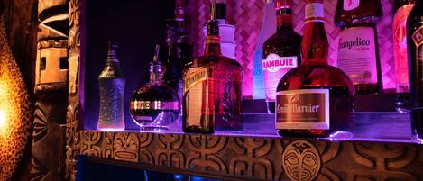 Un bar con varias botellas de licor y un panel de madera decorativo.