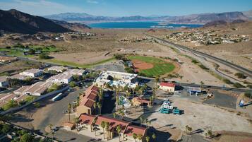 An aerial view of a small town with a baseball field, a parking lot, and a few buildings.