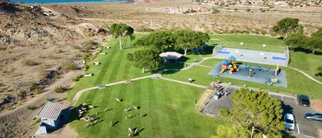 An aerial view of a rural area with a playground, a small building, and a parking lot.