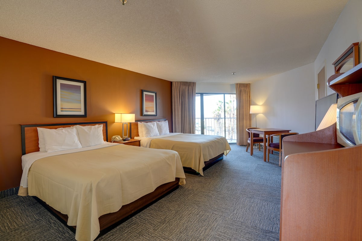 Une chambre d’hôtel avec deux lits, un bureau et une chaise.
