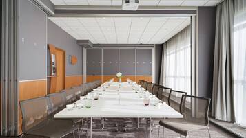 A conference room with a long table, chairs, a projector, and a large window.