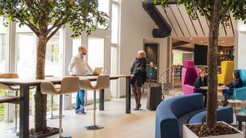 Un espace intérieur moderne doté de coins salon, d’un escalier et de plantes d’intérieur.