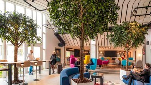 A modern lobby with indoor trees, seating areas, and a bar. - Novotel Metz Amneville Hotel (Hauconcourt)