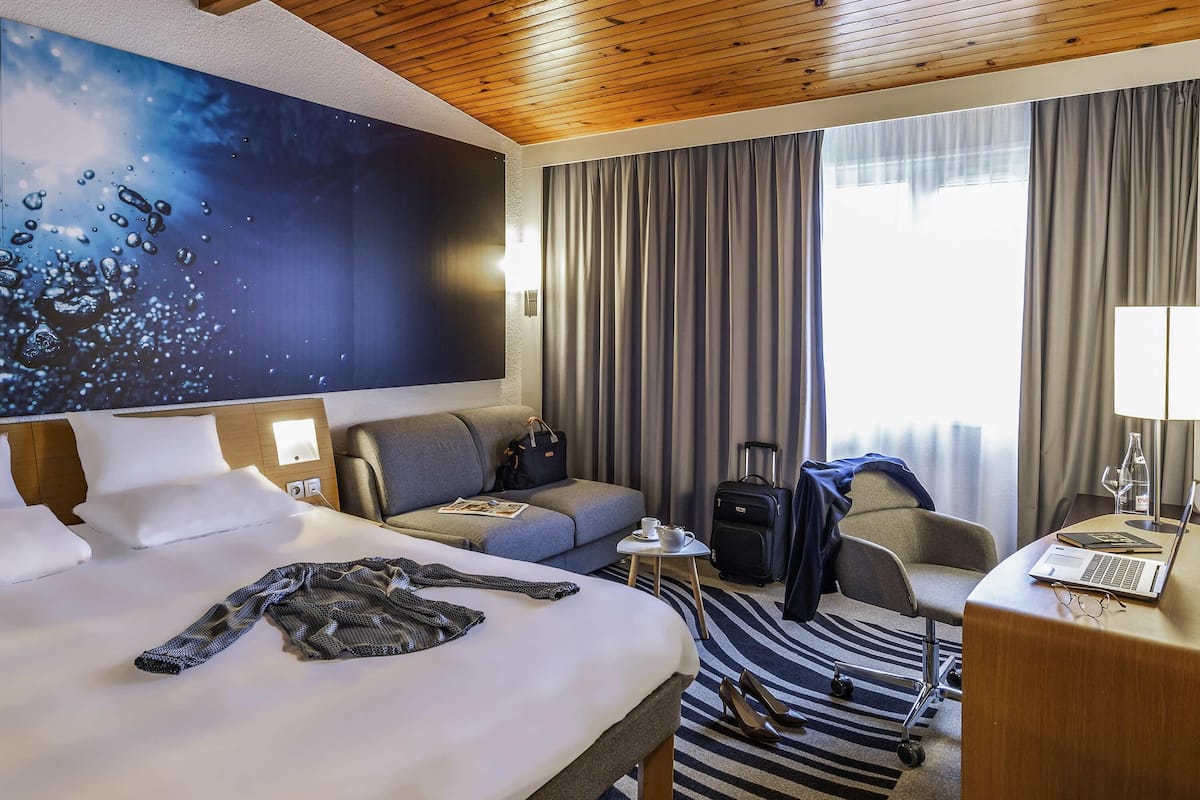 Une chambre d’hôtel équipée d’un lit, d’un canapé, d’un bureau, d’un ordinateur portable et offrant une vue sur l’extérieur.