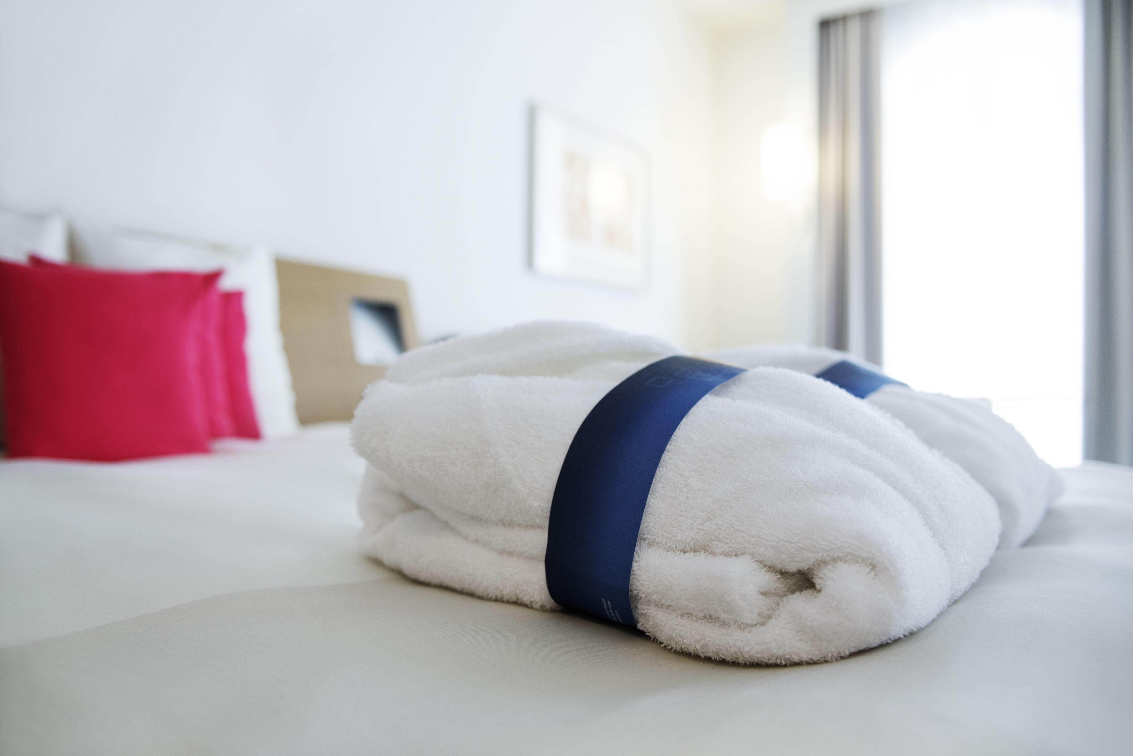 Ein ordentlich bezogenes Bett mit weißer Decke und blauem Handtuch.