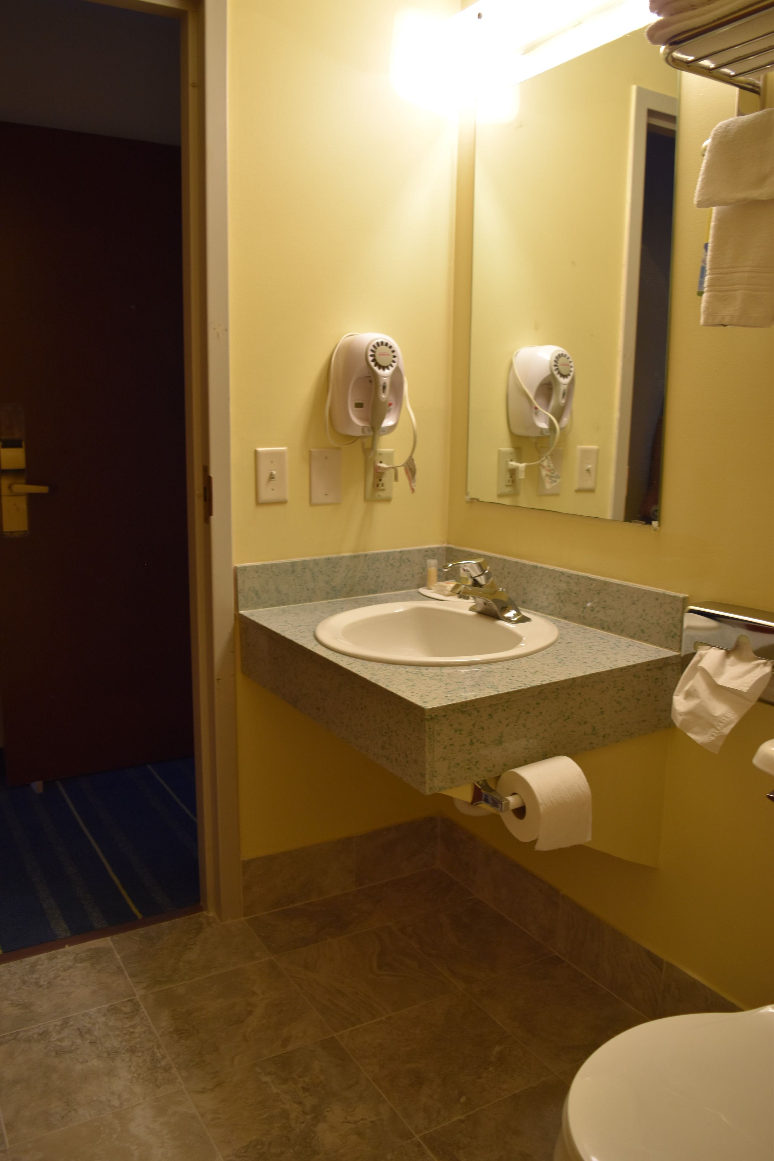 A bathroom with a sink, mirror, towel rack, and toilet.
