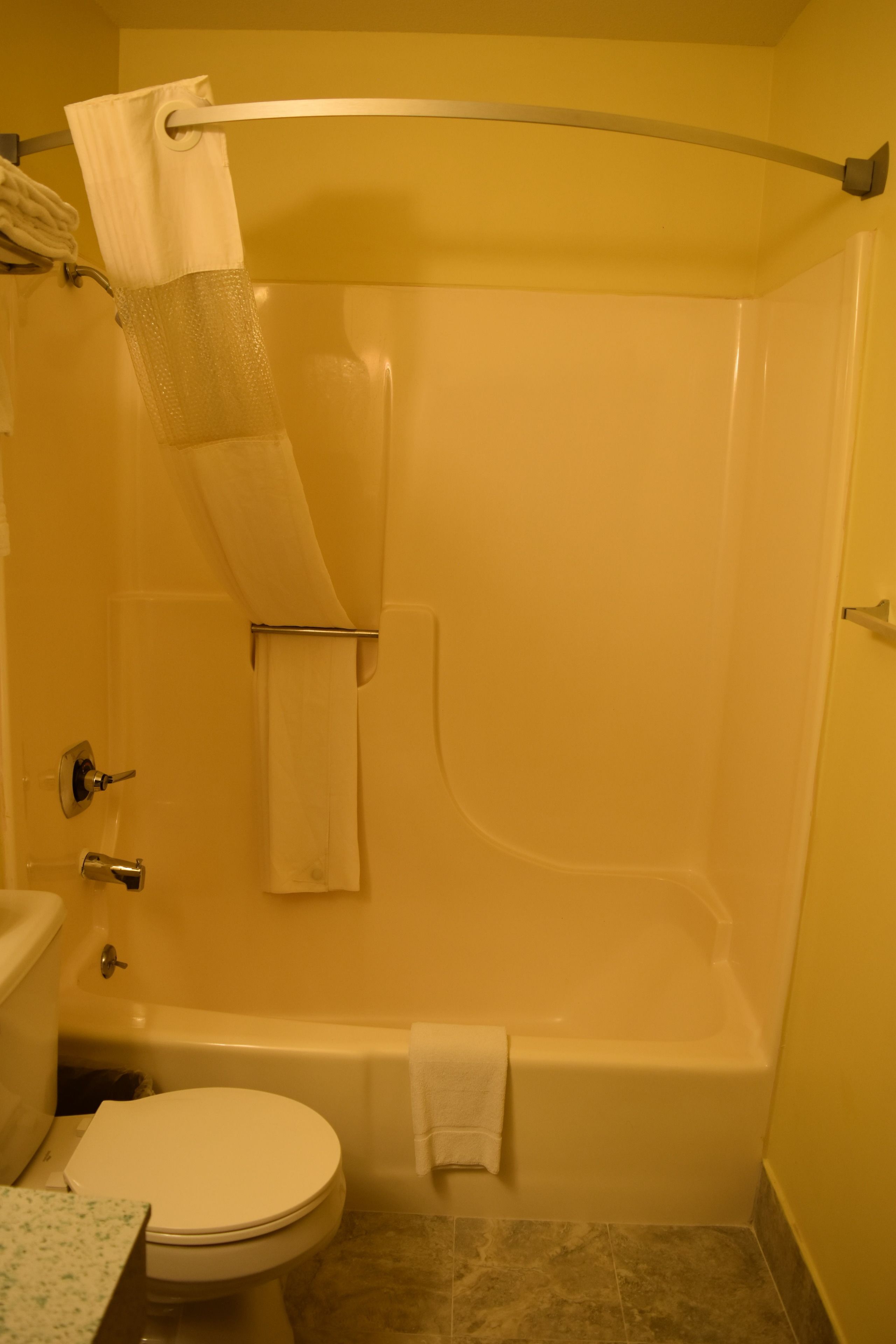 A bathroom with a bathtub, toilet, and a towel rack.