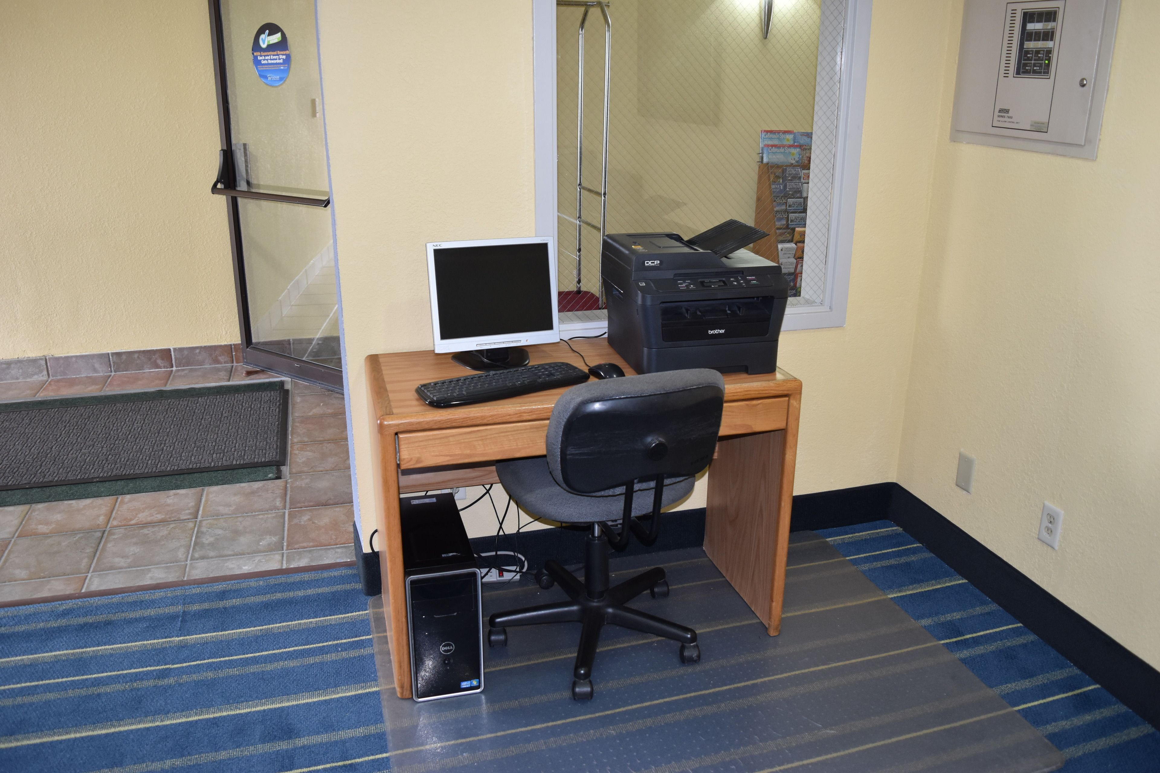 A small office space with a desk, computer, printer, and chair.