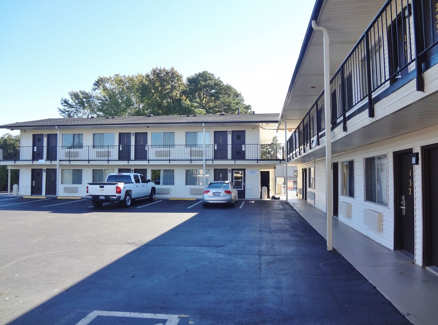 A motel with a two-story structure, a parking lot, and a sign for a 'Ice Machine.'