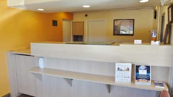 A reception desk with a counter, a clock, and a framed picture on the wall.