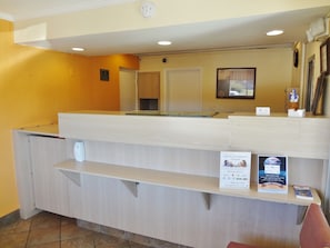 A reception desk with a counter, a clock, and a framed picture on the wall. - Americas Best Value Inn (Reno)