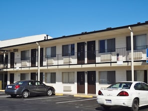 A multi-story motel with numbered rooms, a parking lot, and a clear blue sky. - Americas Best Value Inn (Reno)