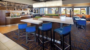 A modern bar area with a counter, bar stools, and a seating area with tables and chairs. - Courtyard by Marriott Southfield (Southfield)