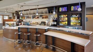A modern bar area with a curved counter, stainless steel stools, and a variety of liquor bottles.