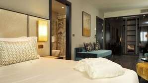 A hotel room with a large bed, a seating area with a sofa and chairs, and a visible bathroom.