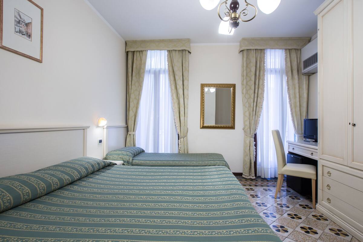 Una camera da letto con due letti, una scrivania, una sedia e un armadio.