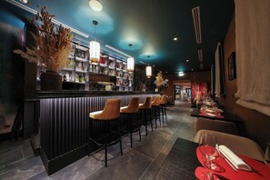 A bar area with a counter, bar stools, and shelves of bottles. - Universo And Nord Hotel (Venice)