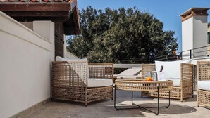A rooftop patio with wicker furniture, a table, and a chair. - Universo And Nord Hotel (Venice)