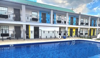 Un hotel de varios pisos con piscina, balcones y techo azul.