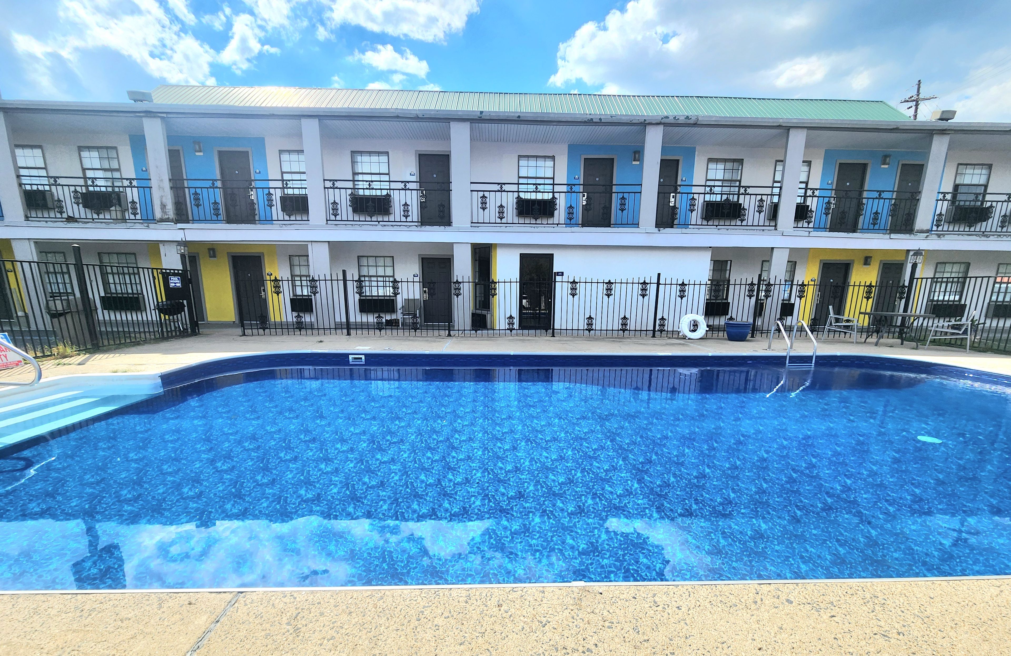 A hotel with a swimming pool, multiple balconies, and a two-story structure.