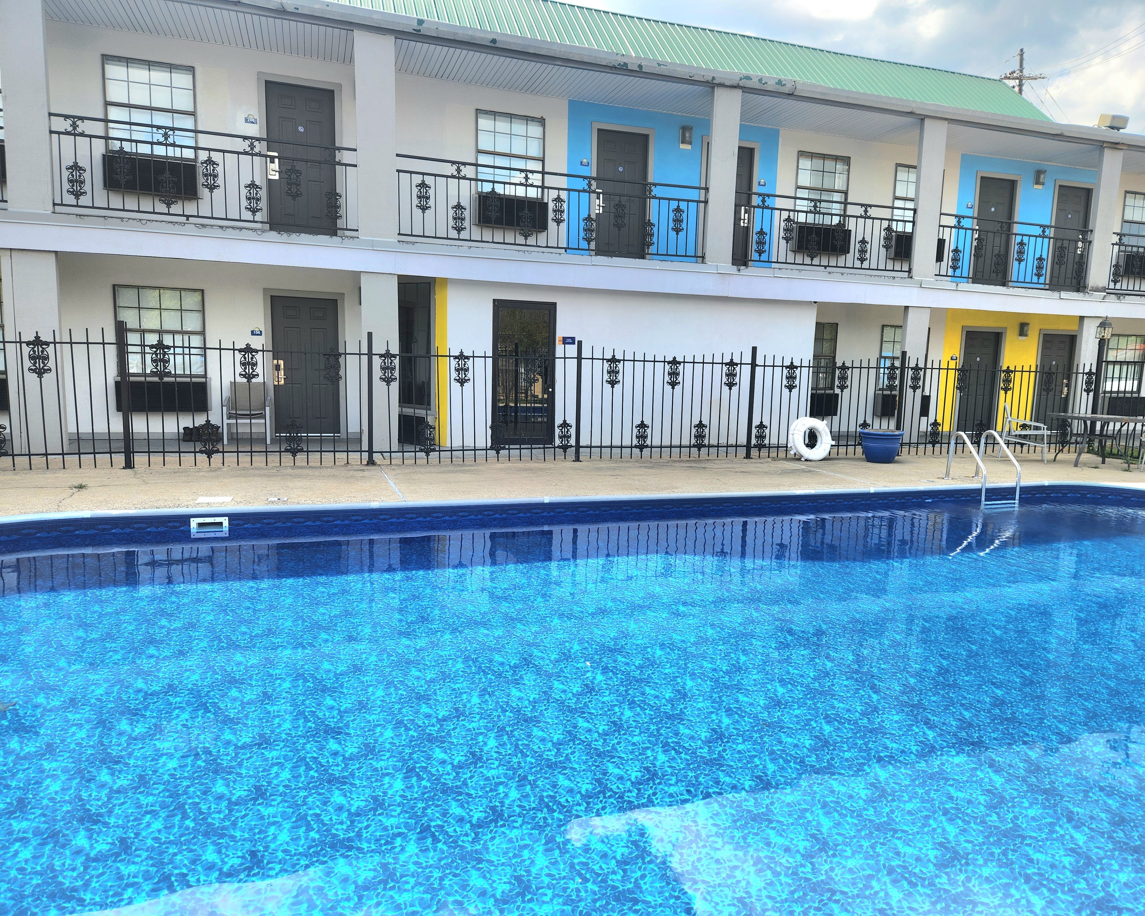 A multi-story hotel with a swimming pool, balconies, and a green roof.