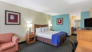 A hotel room with a bed, a desk, a chair, a TV, and a couch. - Days Inn by Wyndham Natchitoches (Natchitoches)