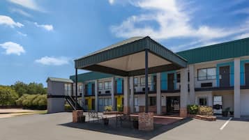 A multi-story building with a covered outdoor seating area, a staircase, and a parking lot.